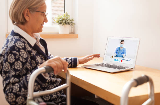 Retired senior elderly woman with mobility problem talking to UK NHS GP female doctor via virtual telemedicine video call Retired senior elderly woman with mobility problem talking to UK NHS GP female doctor via virtual telemedicine video call,holding walking frame,online appointment therapy treatment,telehealth concept doctor of physio therapy online stock pictures, royalty-free photos & images
