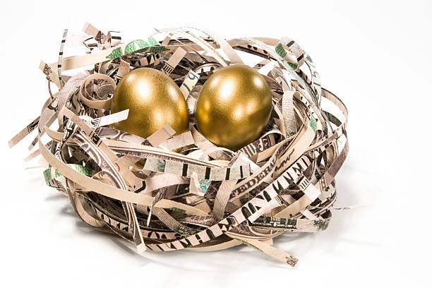 Retirement Nest Eggs Two gold eggs in a nest made of $100 US dollars on white background.Related images: nest egg stock pictures, royalty-free photos & images