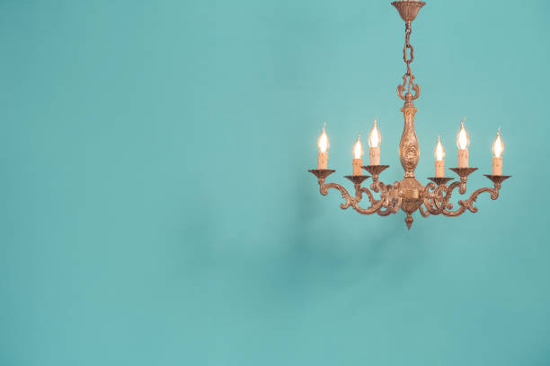 Retro antique old bronze chandelier with bulb lamps shaped candles hanging front mint blue wall background. Nostalgia lighting concept. Vintage style filtered photo stock photo