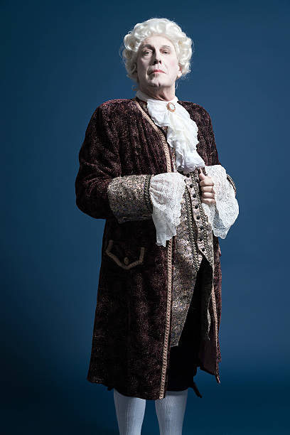 Retro baroque man with white wig standing and looking arrogant. Retro baroque man with white wig standing and looking arrogant. Studio shot against blue. period costume stock pictures, royalty-free photos & images