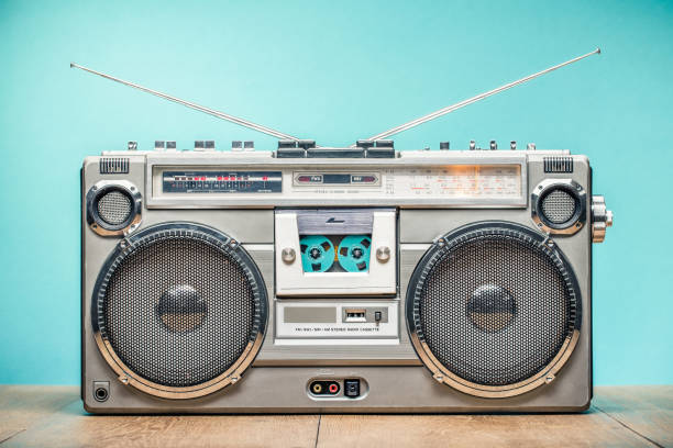 Retro outdated portable stereo boombox radio receiver with cassette recorder from circa late 70s front aquamarine wall background. Listening music concept. Vintage old style filtered photo stock photo