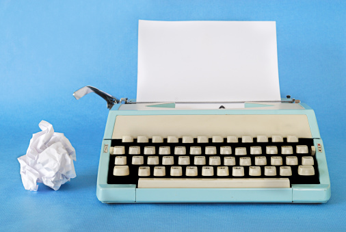Manual Typewriter Circa 1970 with a blank sheet of paper and rejected work alongside