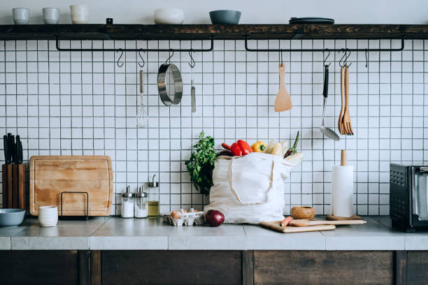 キッチンカウンターにはカラフルで新鮮な有機野菜や食料品でいっぱいの再利用可能なバッグがあります。ゼロ廃棄物ショッピングと持続可能なライフスタイルコンセプト - 台所 ストックフォトと画像