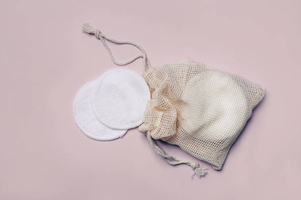 Reusable Bamboo Cotton Makeup Remover Pads in net bag on pink background. Zero-waste, sustainable lifestyle concept stock photo
