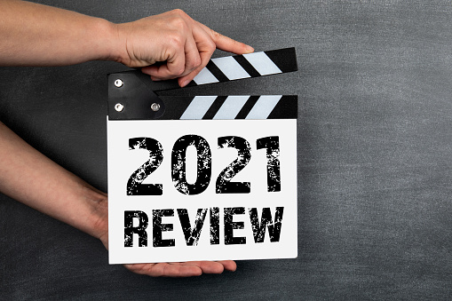 2021 Review concept. White movie clapper on a background of a dark chalk board.