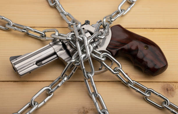 pistola de mano revólver y cadenas de metal sobre fondo de madera, control de armas y concepto de seguridad - gun violence fotografías e imágenes de stock