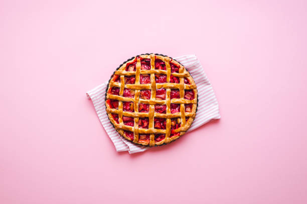 Rhubarb-strawberry pie freshly baked. Lattice crust pie top view Homemade rhubarb and strawberries pie on a pink background, above view. Flatlay with a freshly baked lattice crust pie comfort food stock pictures, royalty-free photos & images