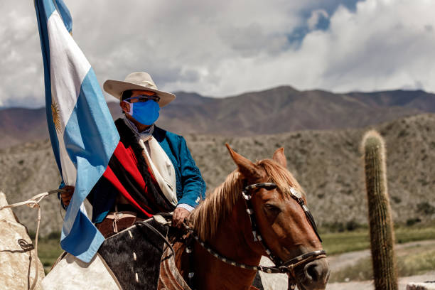 Rider in traditional dress carries the Argentine flag in the festivity of welcoming new tourists Cachi, Argentina - January 8, 2021: Rider in traditional dress carries the Argentine flag in the festivity of welcoming new tourists horse mask photos stock pictures, royalty-free photos & images