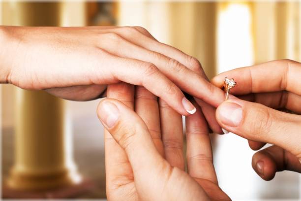 Ring. Close up Groom Putting the Wedding Ring on bride gold ring on finger stock pictures, royalty-free photos & images