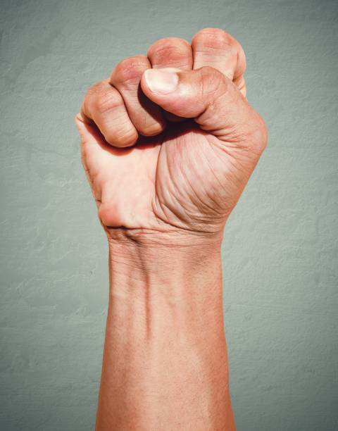Riot protest fist raised in the air. Male clenched fist on dark grunge background. Riot protest fist raised in the air. Male clenched fist on dark grunge background. free jpeg images stock pictures, royalty-free photos & images