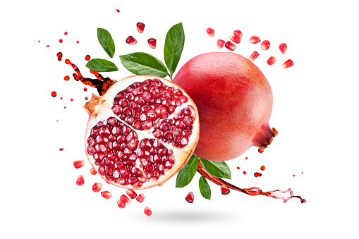 A ripe pomegranate with seeds and leaves flying in the air. Isolated object on a white background. Background with pomegranate fruit. Levitate.