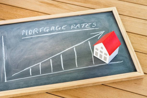 Rising mortgage rate graph on a blackboard lying on a wooden table Graph representing the rise in mortgage interest rates drawn on a chalkboard lying on a wooden table. A model of a house with a red roof is on the chalkboard. Finance and real estate concept. mortgage stock pictures, royalty-free photos & images