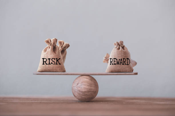 risico- en beloningszakken op een basisbalansschaal in gelijke positie op houten tafel. risicomanagementconcept, toont beleggers gebruik maken van een risk reward ratio om het verwachte rendement van een investering te vergelijken - risk stockfoto's en -beelden