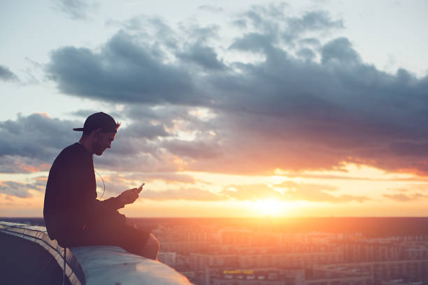 Risky man with smartphone chilling on the roof stock photo