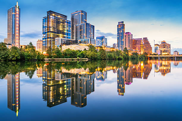 Riverbank Skyline of Austin Texas USA Stock photo of the skyline of downtown Austin, Texas, USA with apartment buildings and office buildings, reflecting in the Colorado River during the dawn twilight blue hour. blue hour twilight stock pictures, royalty-free photos & images