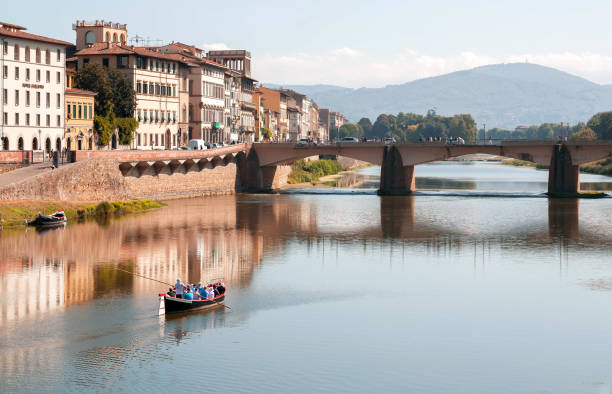 Riverboat with tourists floating past river Arno bridge of ancient Tuscany city Florence, Italy - September 24, 2018: Riverboat with tourists floating past river Arno bridge of ancient Tuscany city on September 24, 2018. Historical Florence is a UNESCO World Heritage Site. arno river stock pictures, royalty-free photos & images