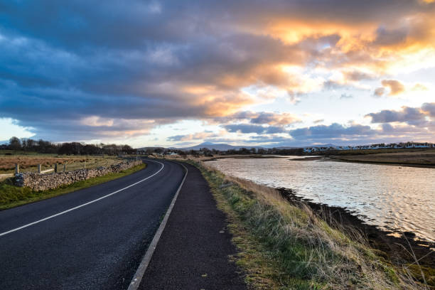 Riverfront Drive A curving road by a river at sunset inishowen peninsula stock pictures, royalty-free photos & images