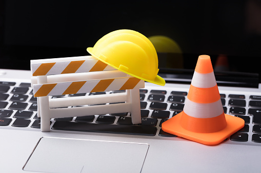 Road Barrier With Hard Hat And Traffic Cone On Laptop Keypad