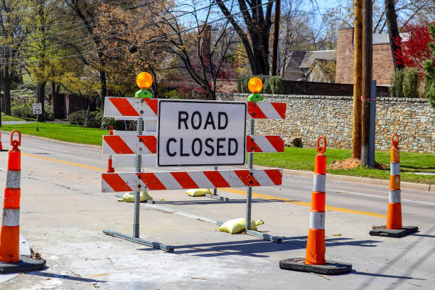 Road closed sign in the middle of four lane highway in residential neighborhood in early spring stock photo