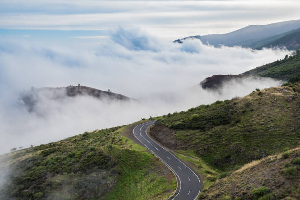 road in mountain landscape over clouds stock photo