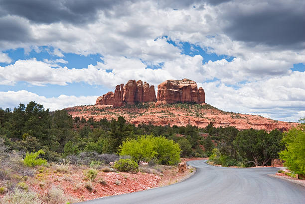 Road Leading to Cathedral Rocks Cathedral Rock is one of the most iconic landmarks in Arizona. It is a natural sandstone butte made up of several discreet columns. It is prominent on the Sedona skyline and one of the most-photographed rock formations in Arizona. Cathedral Rock is located in Yavapai County within the Coconino National Forest. Cathedral Rock sits at an elevation of 4,967 feet. In geological terms Cathedral Rock is carved from the Permian Schnebly Hill formation which is a red sandstone from coastal dunes near the shoreline of the ancient Pedregosa Sea. This view of Cathedral Rock was photographed from Back O Beyond Road in the Village of Oak Creek, Arizona, USA. jeff goulden rock formation stock pictures, royalty-free photos & images