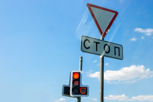 traffic sign give way, stop-stop, electronic traffic light with countdown, against the blue sky with reflection