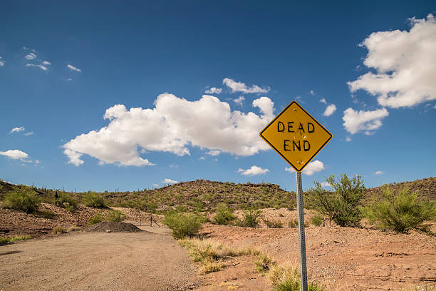 DEAD END Road Sign with Bullet Holes and Peeling Letters DEAD END Road Sign with Bullet Holes and Peeling Letters in Arizona Desert dead end road stock pictures, royalty-free photos & images