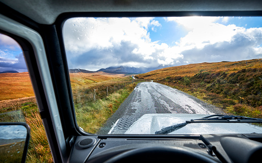 A road through a Scottish landscape seen though a window of a 4x4 near the Fairy Pools