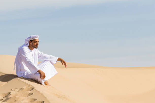 Road to success is in my roots which starts here. Middle Eastern Arab sitting on a sand dune and admiring the nature. agal stock pictures, royalty-free photos & images