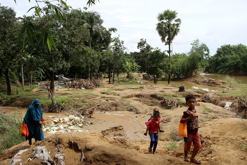 People walk on a flood-damaged road. As a result of climate change, people living in low-lying areas are often affected by floods due to heavy rains. Photo was taken from Sunamganj, Sylhet Division in Bangladesh on 6 July 2022.