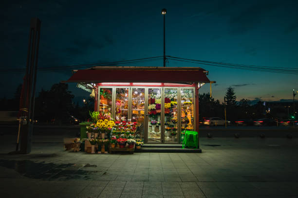 Roadside flower shop during night time. Lonely flower shop late at night, with flowers visible blooming under neon lights. stock photo