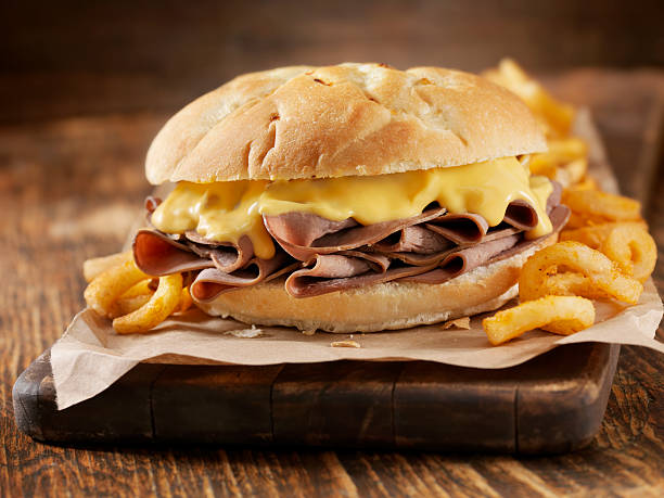 Roast Beef and Cheddar Sandwich Roast Beef  Sandwich with Cheddar Cheese Sauce and Curly Fries- Photographed on Hasselblad H3D2-39mb Camera roast beef sandwich stock pictures, royalty-free photos & images