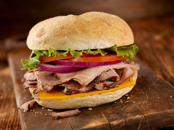Roast Beef  Sandwiches "Roast Beef  Sandwiches with Cheddar Cheese, Lettuce, Tomatoes and Red Onions - Photographed on Hasselblad H3D2-39mb Camera" roast beef sandwich stock pictures, royalty-free photos & images