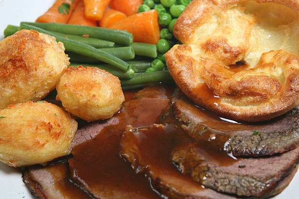 Roast beef with brown gravy and steamed vegetables Traditional British roast beef dinner with yorkshire pudding and vegetables roast dinner stock pictures, royalty-free photos & images