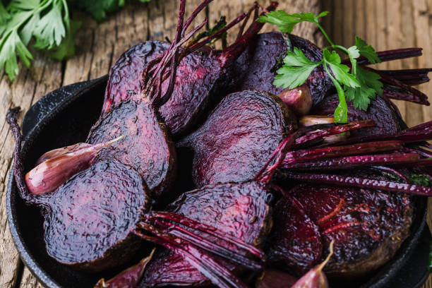 Roasted beets and garlic in cast iron skillet Homegrown roasted beets and garlic in cast iron skillet, fresh parsley herbs on wooden rustic table, plant based food, local produce, close up. Organic vegetables,  healthy  vegan eating, harvest time roasted beets stock pictures, royalty-free photos & images