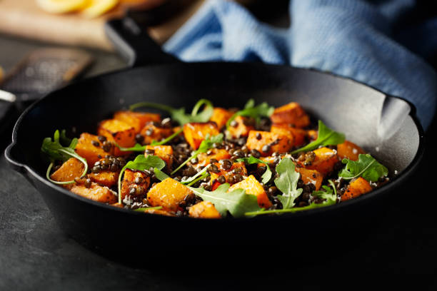 roasted butternut squash with green lentils and rocket leaves stock photo