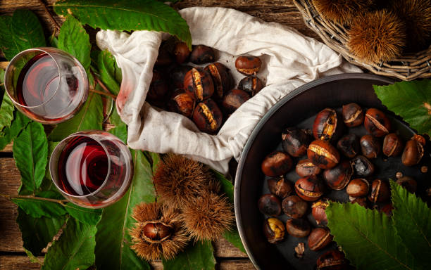 Roasted chestnuts in iron skillet Top view of Roasted chestnuts in iron skillet on wooden table. chestnut food stock pictures, royalty-free photos & images