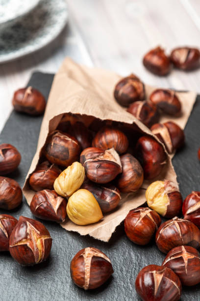 Roasted Chestnuts Roasted chestnuts in a paper bag, lying on a slate chestnut food stock pictures, royalty-free photos & images