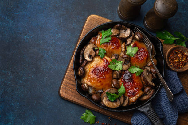 roasted  chicken thighs with mushrooms on cast iron  pan roasted  chicken thighs with mushrooms on cast iron  pan , dark blue concrete background, top view, copy space chicken thigh meat stock pictures, royalty-free photos & images