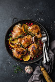 roasted  chicken with orange, cranberry and spicy herbs on pan , black concrete background, copy space, top view,