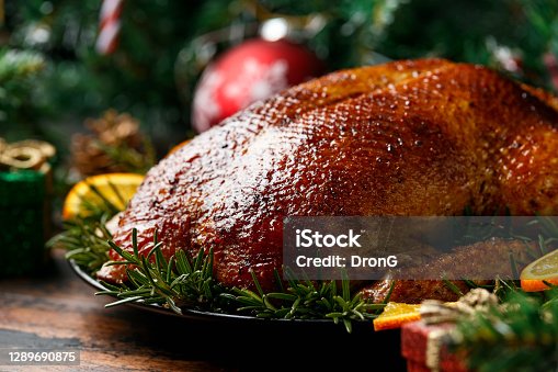 istock Roasted Christmas duck with decoration, gifts, green tree branch on wooden rustic table 1289690875