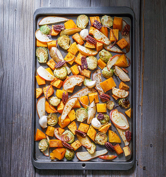 Roasted cut vegetables and fruit on a baking sheet. stock photo
