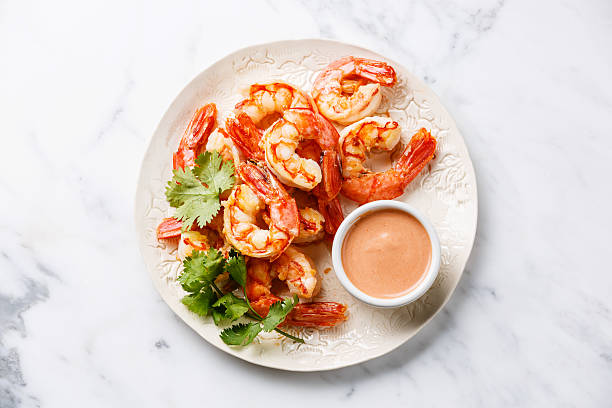 Roasted Prawns with cocktail sauce Roasted Prawns on white plate with cocktail sauce on white marble background cocktail sauce stock pictures, royalty-free photos & images
