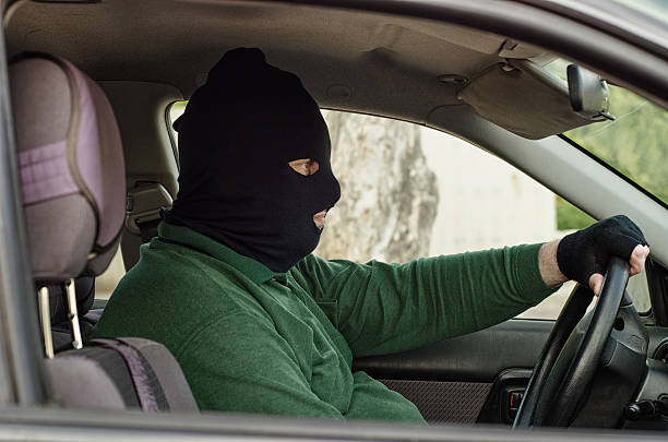 Robber in balaclava inside a car stock photo