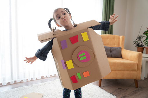 cute child is wearing cardboard robot costume at home