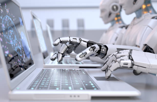 Robots typing on laptops stock photo