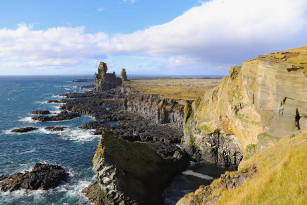 Rock and lava formations along the coastline and the Londrangar basalt cliffs on the southern coast of Snaefellsnes peninsula in West Iceland. The Londrangar basalt cliffs - huge towers of lava. stock photo