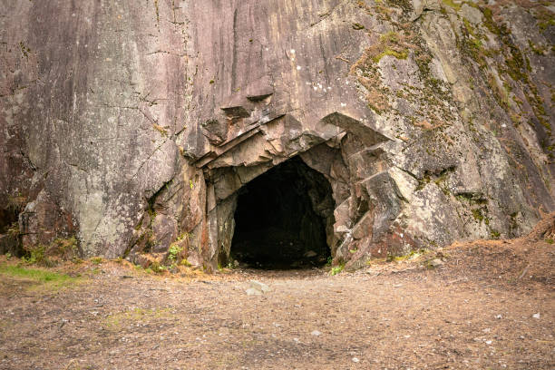 rotsmuur met een donker gat, ingang aan de hol in spro, minerale historische mijn. nesodden noorwegen. nesoddtangen schiereiland. - speleologie buitensport stockfoto's en -beelden