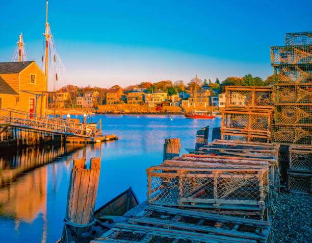 Rockport Harbor and village with its lobster baskets glow in the sun. Lobster Baskets, both metal and wooden, sit on the dock at Rockport Harbor in Massachusetts. The village houses line the water and look old fashioned and inviting. fishing village stock pictures, royalty-free photos & images