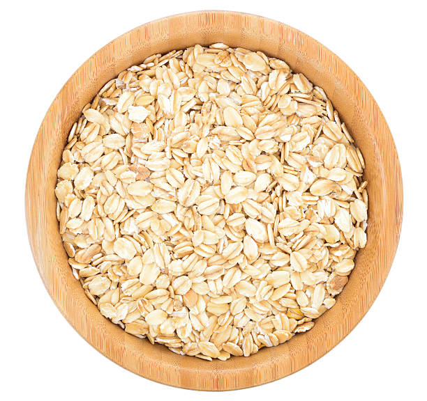 Rolled oats in wooden bowl isolated. stock photo